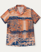 Front of the Last Light at Stearns short-sleeve shirt with an orange and blue sunset reflected across water.
